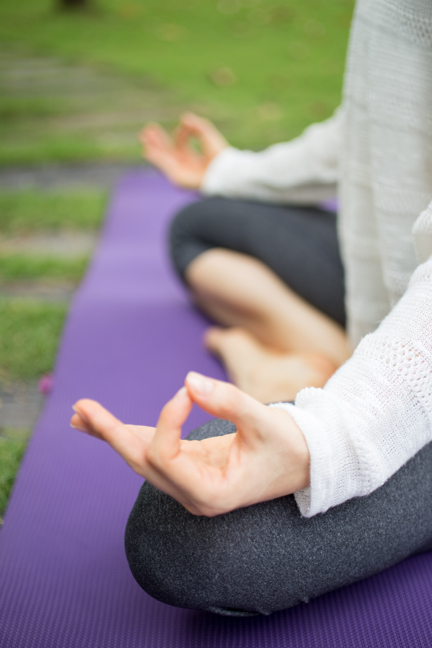 Hand of young woman sitting on mat and meditating